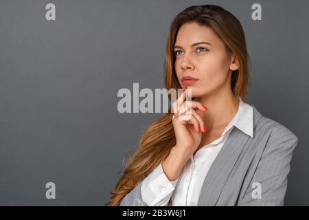 Studio giovane donna business isolato su grigio pensieroso primo piano Foto Stock