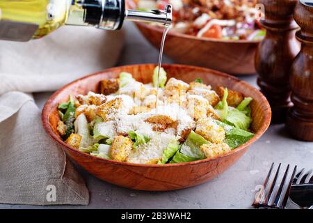 Caesar Salad in una ciotola di legno con lattuga, parmigiano e crostini Foto Stock