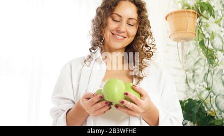 Donna felice senior con capelli ricci con mele verdi. Dieta. Stile di vita sano. Foto Stock