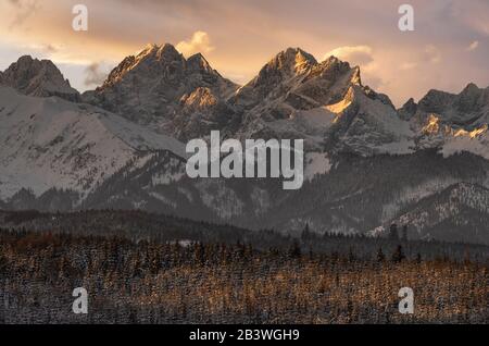 Cime innevate dei Monti Tatra alla luce del sole che sorge Foto Stock