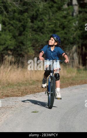 Austin Texas USA, 1998: Ragazza panamaniana-americana di nove anni che si gode in modo sicuro in bicicletta su una strada residenziale collinare. ©Bob Daemmrich Foto Stock