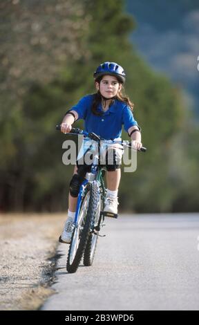 Austin Texas USA, 1998: Ragazza panamaniana-americana di nove anni che si gode in modo sicuro in bicicletta su una strada residenziale collinare. ©Bob Daemmrich Foto Stock