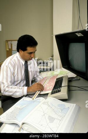 Austin Texas USA: Cartografo ispanico guarda le mappe nel suo ufficio presso il Dipartimento dei Trasporti del Texas. ©Bob Daemmrich Foto Stock