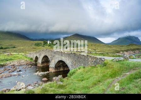 Vecchio ponte di pietra Sligachan con montagne di Cuillin nero sullo sfondo, Isola di Skye, Scozia Foto Stock