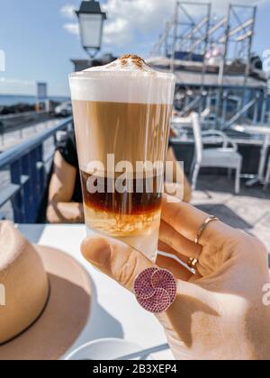 Tenere il tradizionale caffè delle canarie barakito presso il caffè all'aperto. Immagine realizzata sul telefono cellulare Foto Stock