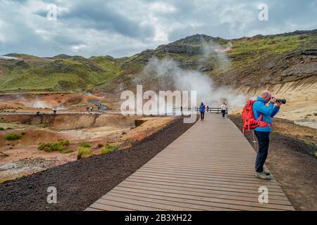 Area geotermica Krysuvik con sorgenti termali e un escursionista solitario, Islanda Foto Stock