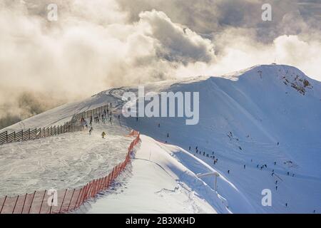 Stazione sciistica. Sochi. Russia. Molti sciatori e snowboarder sullo sfondo di una montagna innevata in tempo soleggiato. Foto Stock