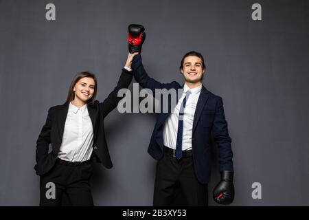 Uomini e donne d'affari nei guanti da boxe vincono gesti su sfondo grigio Foto Stock