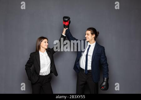 Uomini e donne d'affari nei guanti da boxe vincono gesti su sfondo grigio Foto Stock