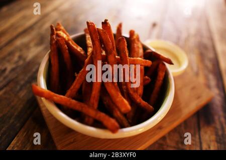 Titolo: Patatine fritte dolce in ciotola su piano rustico in legno Foto Stock