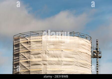 alto edificio in impalcature coperte da striscione bianco Foto Stock