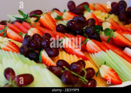Piatto di frutta con uva fresca, mela, ananas, kiwi, mango e fragola matura rossa. Vassoio di frutta colorato migliore salute buon cibo per tutte le età Foto Stock