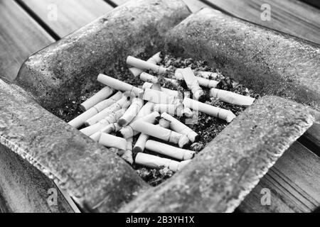 Chiusura del portacenere pieno di sigarette, con l'uomo nel lavoro in  background sul computer portatile e fumare in luoghi chiusi su la mattina  presto Foto stock - Alamy