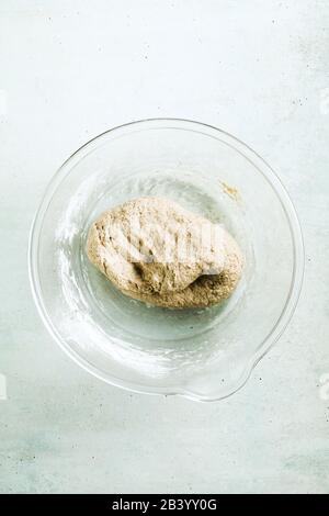 pasta da cucina per il pane pita su un tavolo in una ciotola di vetro, perno di laminazione e coltello Foto Stock