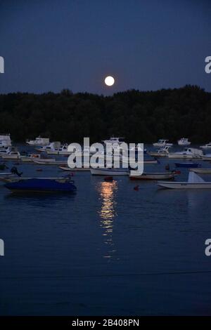 La luna e il riflesso della luna su una piscina d'acqua Foto Stock