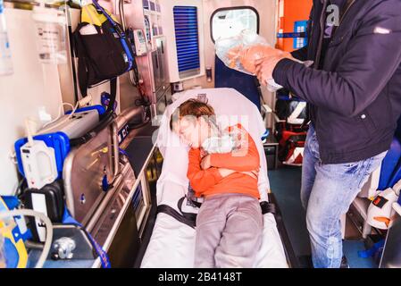 Valencia, Spagna - 29 febbraio 2020: Bambino che giace sulla barella di un'ambulanza durante un esercizio scolastico in caso di pandemia di virus. Foto Stock