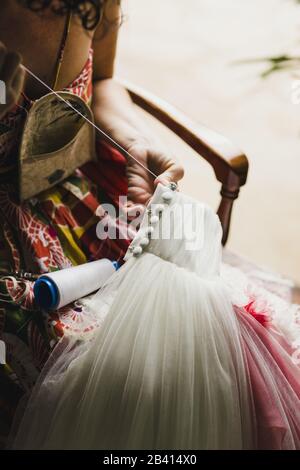 Femmina patching sarta un abito da sposa con filettatura e aghi in un modo a mano a casa. Foto Stock