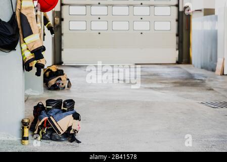 Stivali e giacca da fuoco sul pavimento del garage di una stazione antincendio. Foto Stock