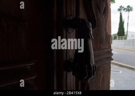 Battente della porta a mano in ferro su vecchia porta in legno. Foto Stock