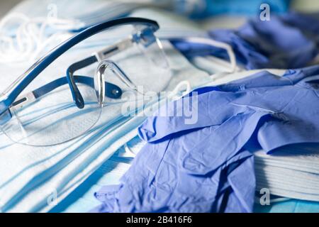 Dispositivi di protezione individuale, un paio di occhiali di sicurezza, maschere blu e guanti in nitrile blu per prevenire la diffusione di infezioni. Foto Stock