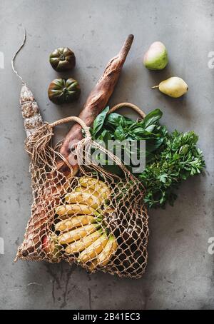 Borsa ecologica con ingredienti freschi e salsiccia, fondo grigio in cemento Foto Stock