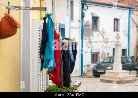 Vestiti appesi davanti alla finestra a Ericeira, Portogallo Foto Stock