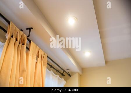 Tenda moderna nell'hotel con un'atmosfera calda. Tende gialle, finestre, multi-livello soffitto.Nuova proprietà immobiliare, senza persone. All'interno di un elegante angolo Foto Stock