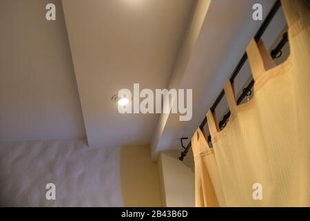 Tenda moderna nell'hotel con un'atmosfera calda. Tende gialle, finestre, multi-livello soffitto.Nuova proprietà immobiliare, senza persone. All'interno di un elegante angolo Foto Stock