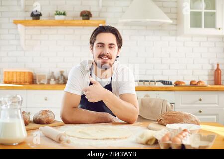 Panettiere maschio bearded uomo sorridente sullo sfondo di pane fresco nella cucina da forno Foto Stock