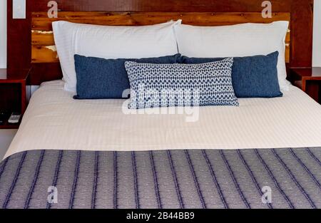 Un letto appena fatto con biancheria pulita e cuscini decorativi pronti per l'uso Foto Stock