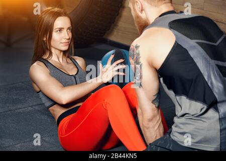 Allenatore aiuta una giovane bella sportivo in palestra facendo esercizi. Contesto di concetto di idoneità. Foto Stock