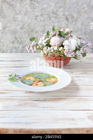 Gnocchi di zuppa e gamberetti serviti con porri. Su vecchio sfondo bianco di legno. Foto Stock