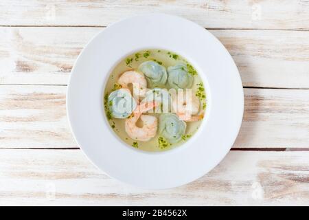 Gnocchi di zuppa e gamberetti serviti con porri. Su vecchio sfondo bianco di legno. Foto Stock