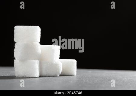 Zollette di zucchero impilati insieme contro uno sfondo nero Foto Stock