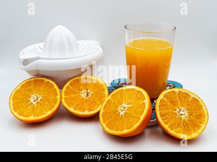 Bicchiere di succo d'arancia fresco con frutta a fette e spremitore, isolato su bianco. Foto Stock