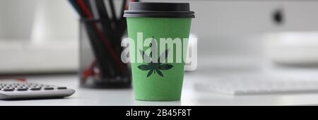 Il caffè verde tazza con il logo di cannabis su office tabl Foto Stock