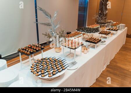 Tavolo bianco con antipasti e stoviglie diversi serviti da azienda di catering Foto Stock