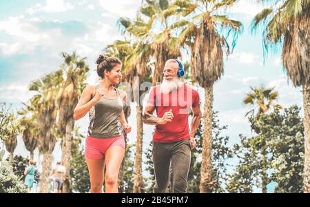 Coppia di amici felici di fitness che corrono all'aperto - Joggers persone che si allenano in un luogo tropicale - Jogging, sano stile di vita e concetto di sport - Focus o Foto Stock