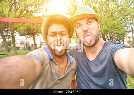 Due migliori amici multirazziali che prendono selfie con la macchina fotografica del telefono mobile - gente multi etnica giovane che ha divertimento che fa i volti divertenti - amicizia interracial Foto Stock