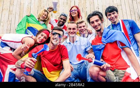 Felici tifosi di sport divertirsi durante il gioco del mondo di calcio - giovani tifosi allo stadio prima di partita di calcio con Air Horn, bandiere e megafono - Friendsh Foto Stock