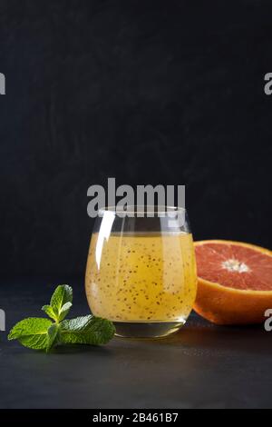 Succo d'arancia tropicale in vetro con semi di chia su sfondo nero. Primo piano. Formato verticale. Foto Stock