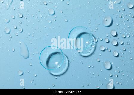 Lenti a contatto su sfondo blu con gocce d'acqua, primo piano Foto Stock