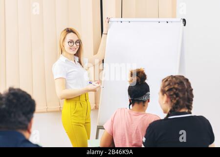 Allegra giovane donna moderna che offre una presentazione al popolo internazionale multirazziale Foto Stock