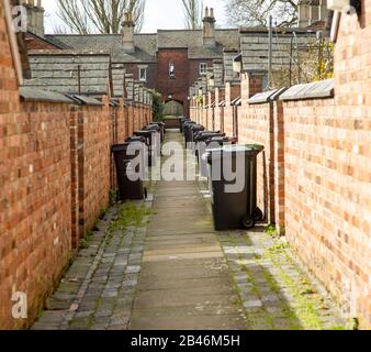 Bidoni dei rifiuti nel vicolo posteriore delle case a schiera nel villaggio ferroviario, Swindon, Wiltshire, Inghilterra, Regno Unito Foto Stock