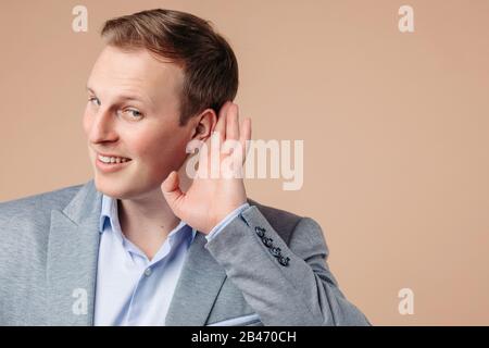Ritratto di bell'uomo in grrey e blu ufficio vestito ascoltare per qualcosa e sorrisi Foto Stock