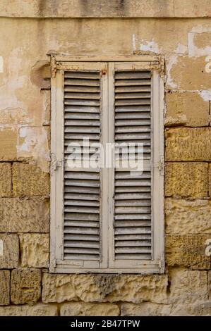 Vecchia serranda in legno in una parete della casa costruita dei blocchi di pietra Foto Stock