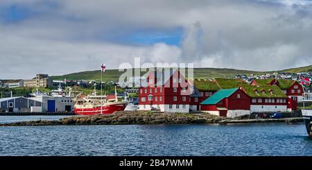 Danimarca, penisola di Tinganes, Torshavn, Streymoy, Isole Faroe. Tinganes è la posizione storica del landsstýri faroese (governo), ed è una parte centrale di Tórshavn. Il nome Tinganes significa 'molo del parlamento' o 'punto del parlamento' a Faroese. Molte delle case in legno di Tinganes sono state costruite nei secoli 16 e 17 e hanno il tipico colore rosso così come il tetto d'erba, che è molto comune sulle isole Faroe. Foto Stock