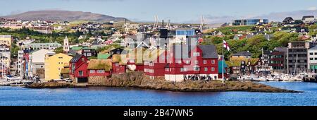 Danimarca, penisola di Tinganes, Torshavn, Streymoy, Isole Faroe. Tinganes è la posizione storica del landsstýri faroese (governo), ed è una parte centrale di Tórshavn. Il nome Tinganes significa 'molo del parlamento' o 'punto del parlamento' a Faroese. Molte delle case in legno di Tinganes sono state costruite nei secoli 16 e 17 e hanno il tipico colore rosso così come il tetto d'erba, che è molto comune sulle isole Faroe. Foto Stock