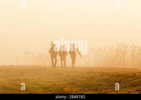 Birdwatchers camminare nella nebbia una mattina presto Foto Stock