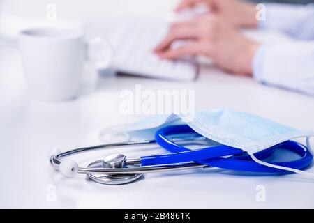 Concetto di business - giovane donna medico femminile che lavora in ufficio con il computer, digitando record medico elettronico, sfondo tabella bianca, primo piano, copia Foto Stock